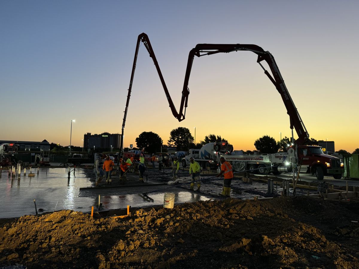 Crew placing concrete with a pump truck at sunset