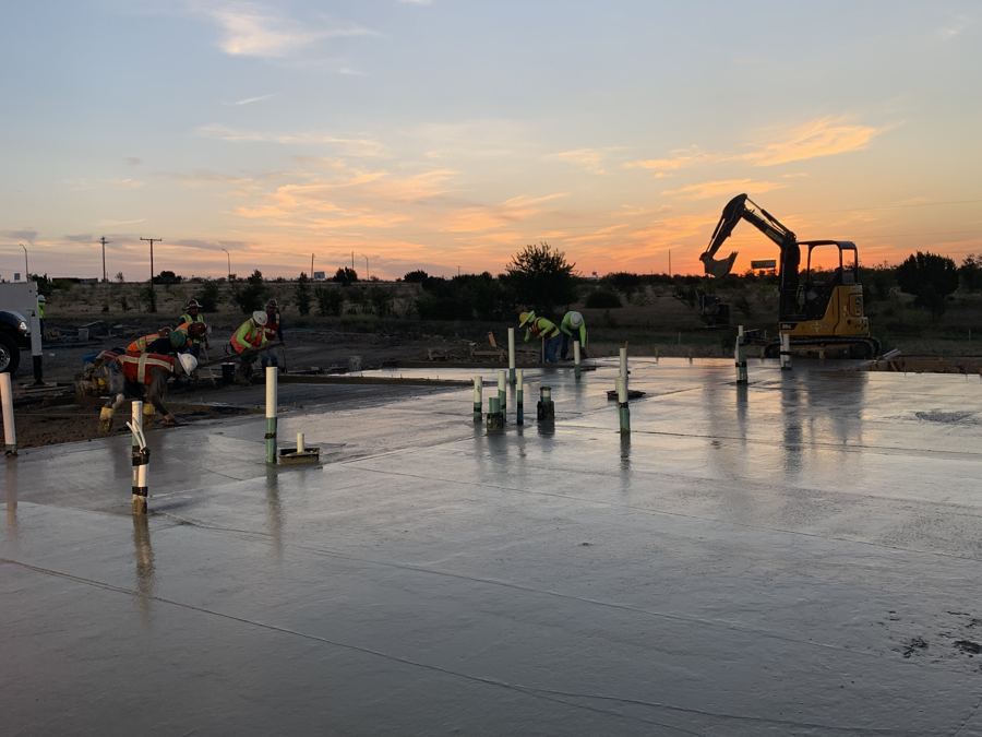 Crew finishing a commercial foundation at sunset